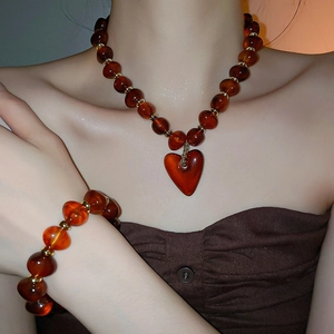 Detail of amber acrylic beaded heart necklace and bracelet set on a female model