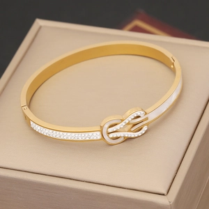 Macro detail of gold knot bracelet with white enamel and sparkling inlaid crystals