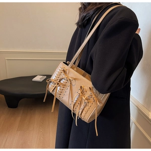 Detail showing khaki PU leather tote with metallic rivets and lace-up bow design