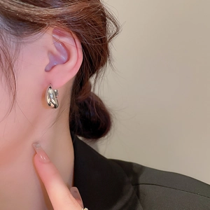 Gros plan sur des boucles d'oreilles géométriques argentées au fini métallique poli miroir