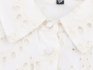 Close-up of white cotton shirt dress with eyelet embroidery and round fabric buttons