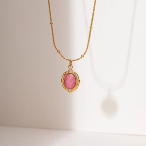 Detailed view of an 18K gold-plated oval pink gemstone pendant with vintage textures