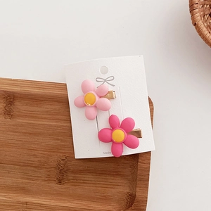 Detailed view of pink flower hair clips with yellow centers on a white display card