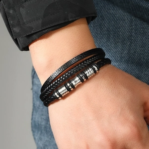 Close-up of triple-layer woven black leather bracelet with silver metal beads on wrist