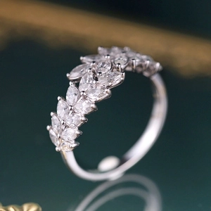 Elegant silver wheat ear ring with marquise-cut gems on reflective green surface