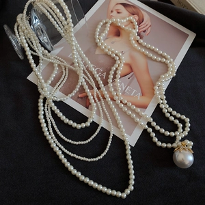 Close-up of elegant multi-layered pearl necklace with large baroque pendant and gold bow