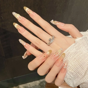 Macro detail of almond press-on nails with champagne glitter, pearls and gold textures