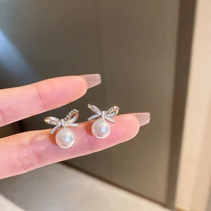 Détail macro de boucles d'oreilles nœud doré avec cristaux brillants et perles blanches