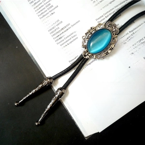 Macro view of blue turquoise stone pendant and ornate metallic tips of the Bolo tie