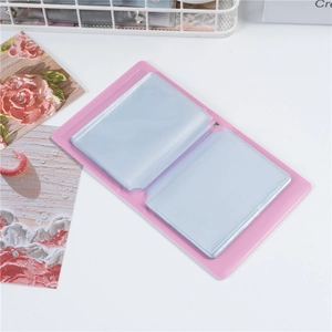Close-up of pink mini photo album with transparent inner pockets on a white desk