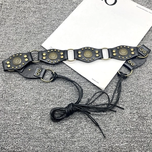 Close-up of black leather Y2K belt featuring brass rivets and round metal ring connectors