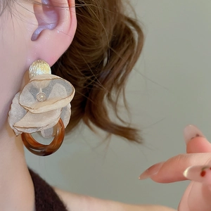 Macro detail of elegant floral drop earrings with champagne tulle and amber resin ring