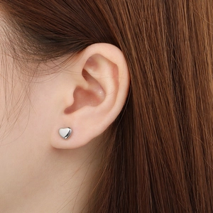 Gros plan de boucles d'oreilles cœur en argent poli portées par un mannequin