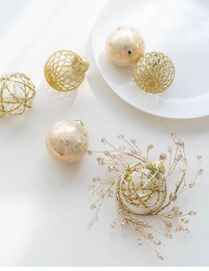 Close-up of gold and white 6cm painted Christmas balls with glitter on white surface
