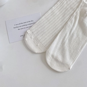 Detailed view of white ribbed mid-calf socks with breathable vertical texture and cotton fabric