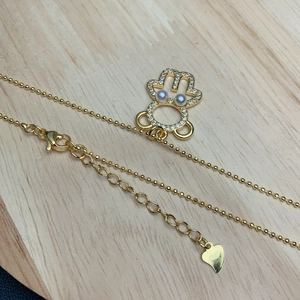 Golden bear pendant necklace with sparkling zircon and imitation pearls on a wood background