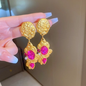 Detailed close-up of vintage gold floral earrings with pink gemstones and pearls