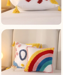 Detail of tufted rainbow pillow with yellow tassels and embroidered dots on white cotton