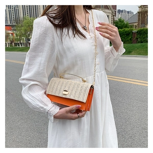 Detail of woven flap on orange and beige handbag with gold metal handle and chain strap