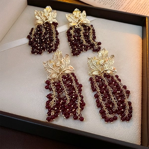 Detail of vintage gold leaf earrings with dark red bead tassels in a jewelry box
