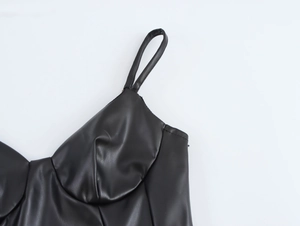 Détail de la robe en similicuir noir montrant la couture des bretelles et la texture