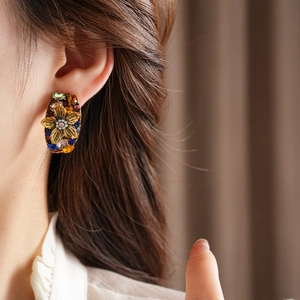 Close-up of vintage flower earrings with multicolored gemstones worn by a model