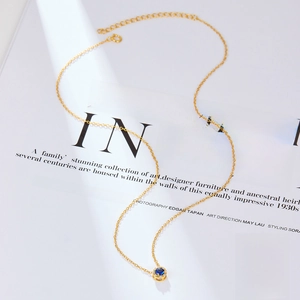 Macro shot of S925 sterling silver gold necklace featuring a blue gemstone pendant