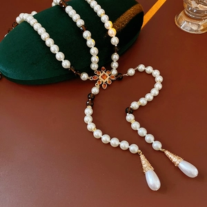 Detail view of vintage multilayer pearl necklace with gold floral pendant on green velvet