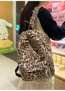Detail of leopard print corduroy backpack featuring white decorative drawstrings and straps