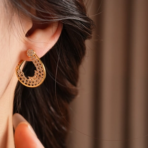 Close-up of gold flower hoop earring with pavé zircon stones worn by a model