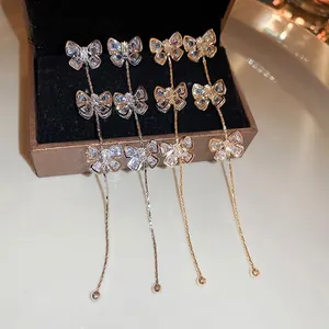 Boucles d'oreilles pendantes nœud en zircon avec pompons en finitions argent et or