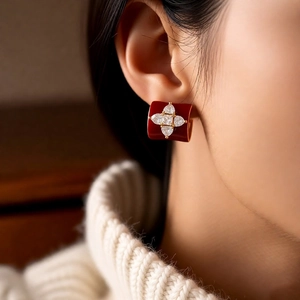 Détail de créole en émail rouge avec fleur dorée et pavé de zircons portée par un modèle