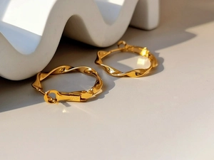Dettaglio del marchio S925 su orecchini a cerchio dorati con design a spirale