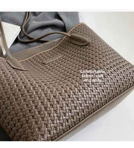 Close-up of the grey woven tote bag showing detailed faux leather texture and shoulder strap