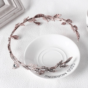 Detail of rose gold leaf bridal tiara with clear crystals wrapped around a white teacup