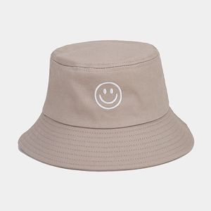Gros plan d'un chapeau bob en coton kaki avec un motif smiley blanc brodé sur le devant