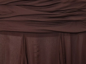 Macro view of sheer dark brown chiffon fabric with pleated texture and translucent grain