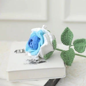 Handcrafted blue and white crochet rose on a vintage book with soft plush background