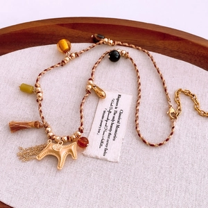 Close-up of ethnic braided rope necklace with golden horse pendant and silk tassels