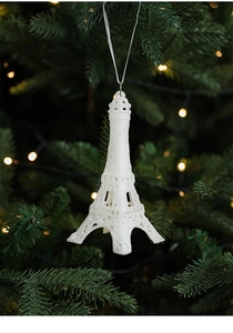 Sparkling white Eiffel Tower Christmas ornament hanging on a festive green pine tree