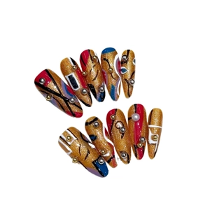 Handmade press-on nails with colorful abstract lines and 3D metallic beads on gold glitter