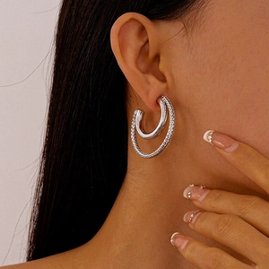 Close-up of textured double-layer C-shaped silver hoop earrings on model ear