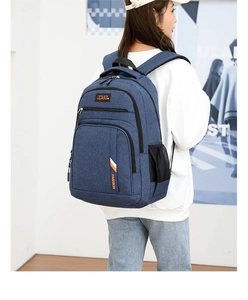 Blue business laptop backpack on a person's back with multi-zipper layers and side mesh pockets