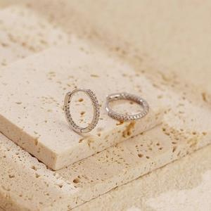 Macro shot of silver paved diamond hoop earrings on natural stone textures