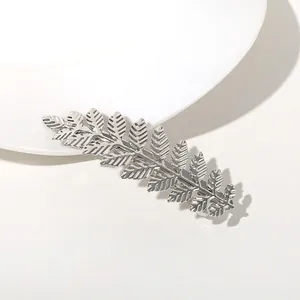 Detailed close-up of a silver metal leaf hair clip with fine texture and spring steel clamp