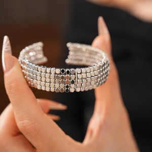 Détail d'un bracelet manchette argenté à plusieurs rangées de perles sur un mannequin