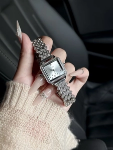 Close-up of a silver square women's watch with full diamond inlay on a car seat