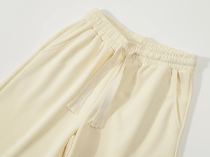 Detailed macro view of cream sports shorts featuring elastic waistband and ribbed texture