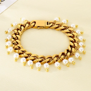 Macro detail of a 9mm gold Cuban chain bracelet with elegant white pearl charms