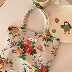 Close-up of floral cotton tote with rose patterns and simple wish label on white table